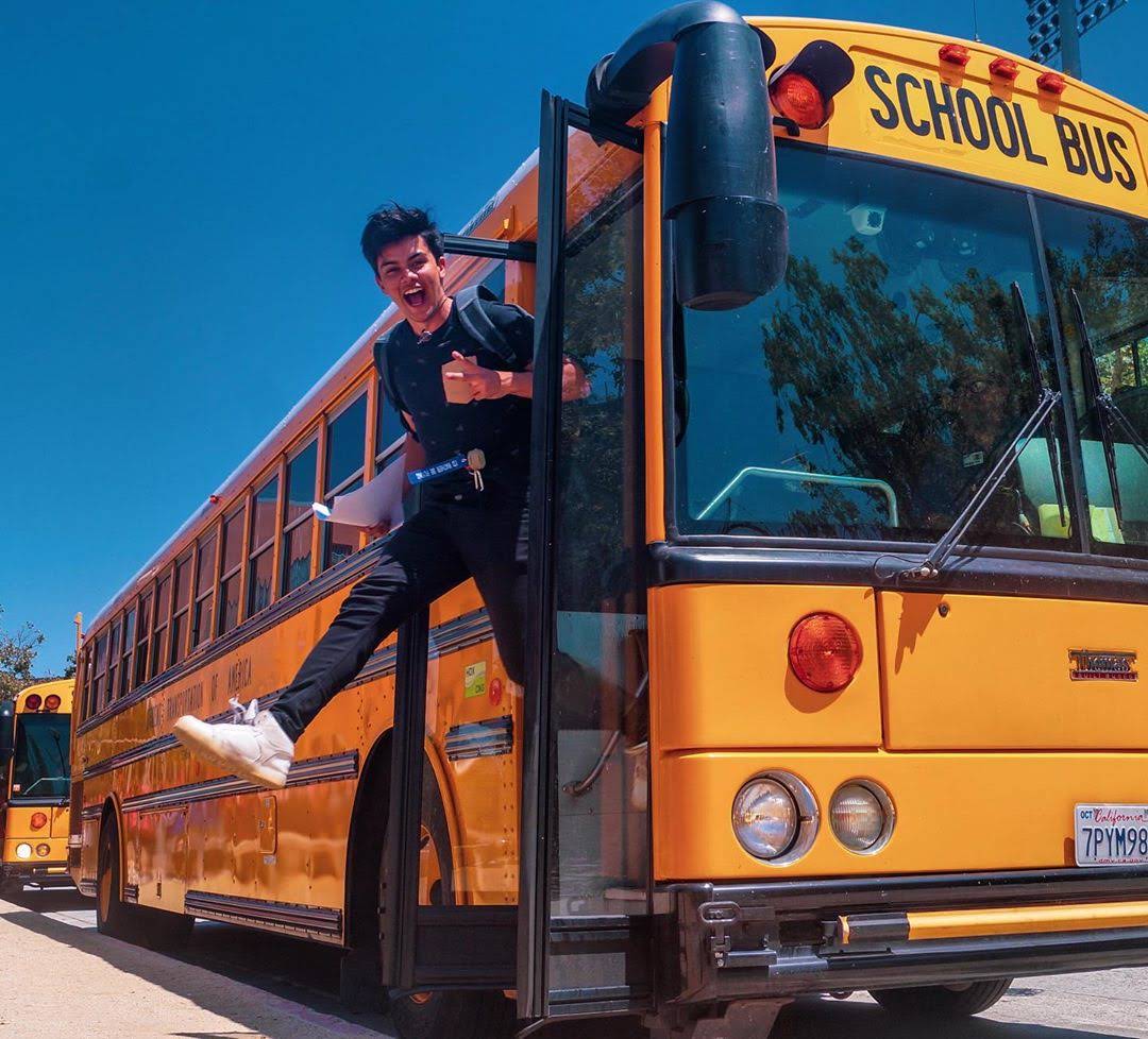 Aluno saindo de um onibus escolar americano em um dia de sol na California
